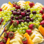 Authentic buffet, assorted fresh fruits, berries and citrus fruits. Morning atmospheric lighting, fashionable trendy spot soft focus. Preparation for design creative menu.